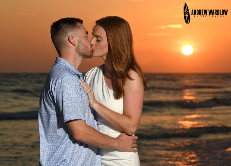 A couple share a sunset kiss after getting engaged during a beach proposal photo session in Panama City Beach, Florida. 