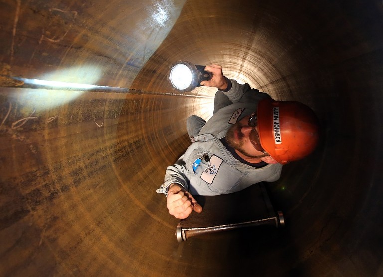 ustin Johnson visually inspects the inside of a pipe at Berg Steel Pipe Corp. in Panama City. (Panama City Photographer | Andrew Wardlow)