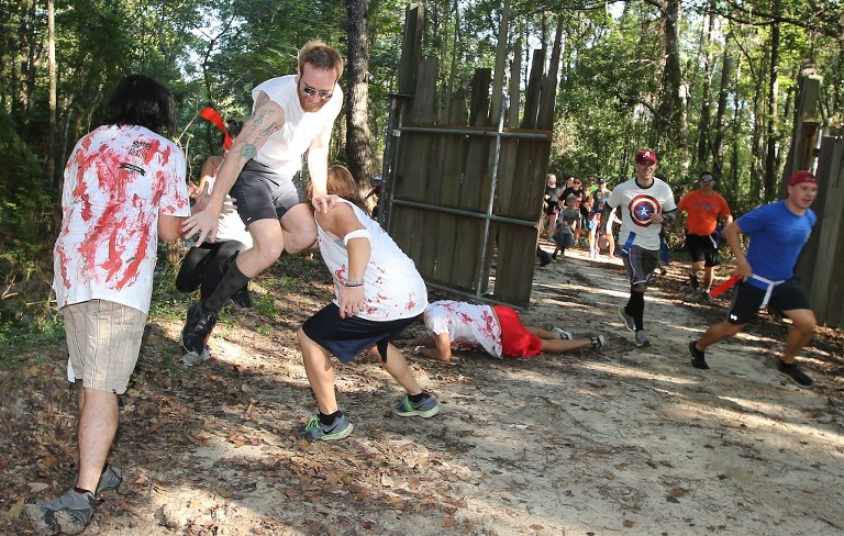 A runner narrowly escapes a group of zombies during third annual Running Scared Zombie 5k Run at Harder's Park in Panama City. (Panama City Photographer/Andrew Wardlow)