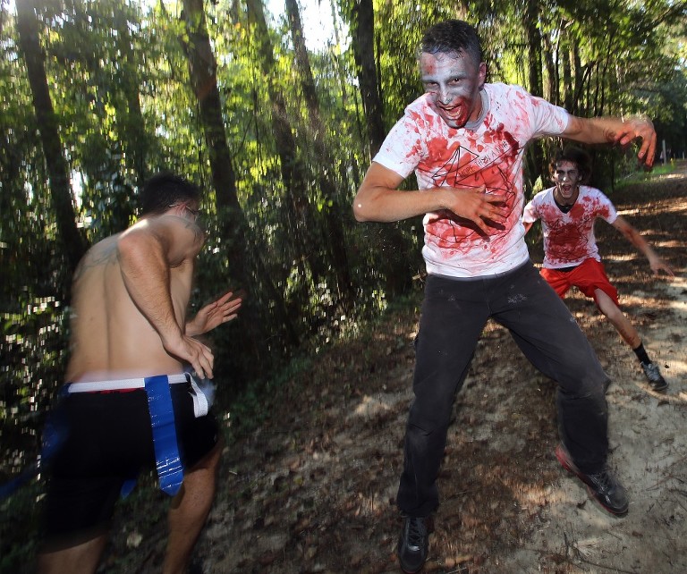 Zombie Johnathon Garrett Jr. gets airborne while scaring runners during the third annual Running Scared Zombie 5k Run at Harder's Park in Panama City. (Panama City Photographer/Andrew Wardlow)