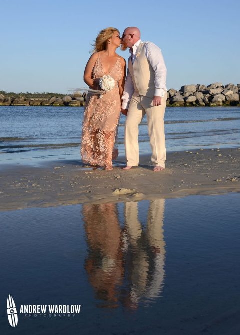 Man and woman kissing with their reflection in the water at St. Andrews State Park in Panama City Beach, Florida taken by Panama City Beach photographer Andrew Wardlow.
