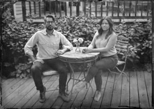 Tintype or wet plate photo of a couple sitting at a table.