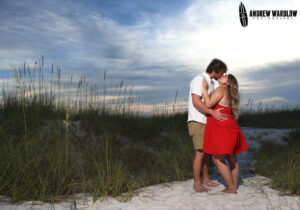 A couple kisses in the dunes at sunset in Panama City Beach, Florida.