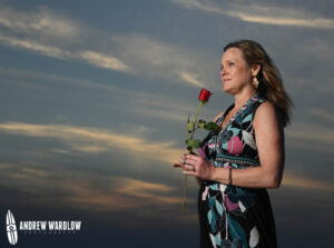 A young woman holds a rose while being photographed at sunset in Panama City Beach, Florida.