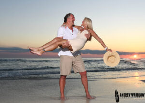 A man carries a woman at sunset while they are photographed in Panama City Beach, Florida.