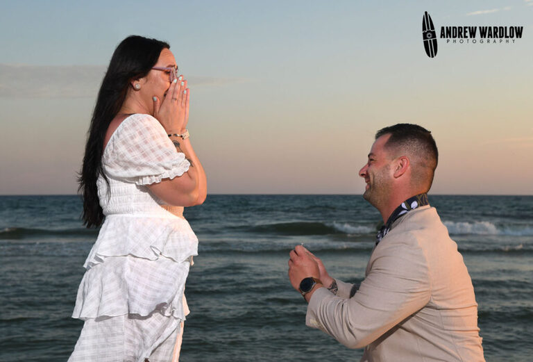 A woman shows surprise as a man proposes to her during a beach proposal photo session in Panama City Beach, Florida.
