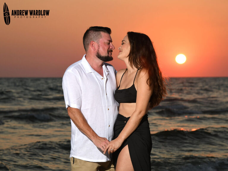 A happy couple poses for a sunset portrait after getting engaged in Panama City Beach, Florida.